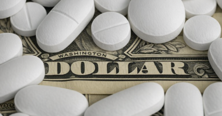White prescription pills resting on a U.S. dollar bill, symbolizing the cost burden of medications and pharmacy benefits.