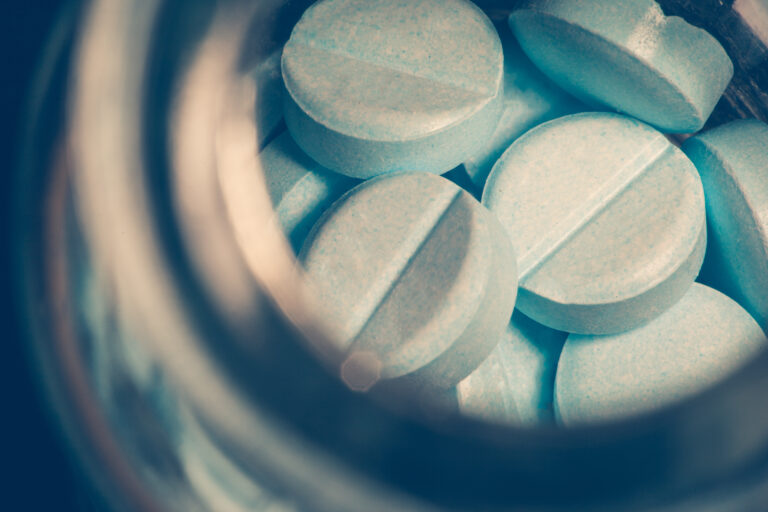 A crossed processed bottle of prescription pills