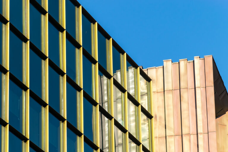 Modern office building with interconnected glass windows and metallic architectural elements, representing the strength and alignment of organizations working together.