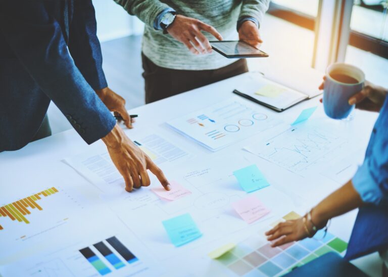 Team members analyze data and planning materials during a discussion of pharmacy benefit management and biosimilar market strategies.