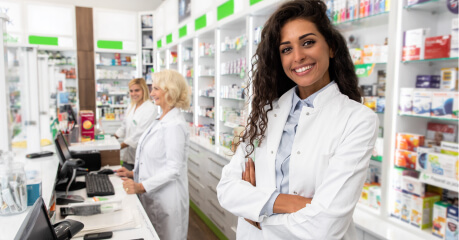 female pharmacist standing behind counter with her arms crossed