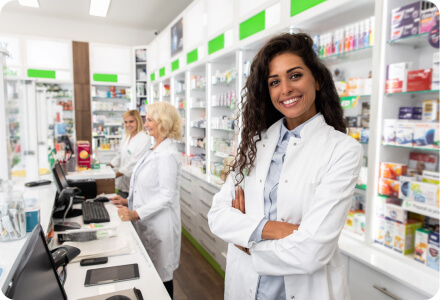 female pharmacist standing behind counter with her arms crossed