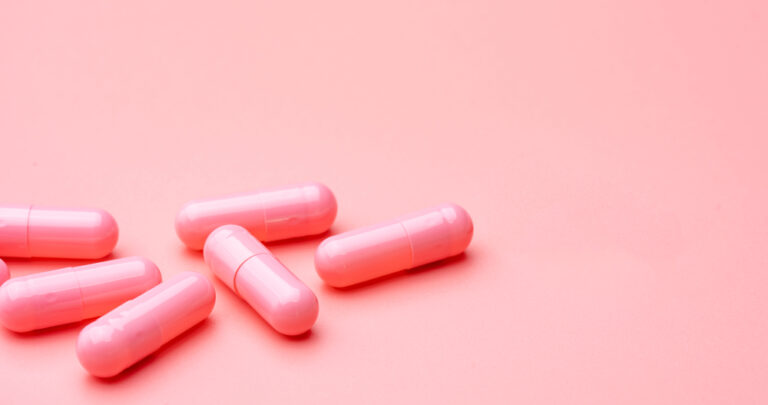 Pink capsule pills on a lighter pink studio background