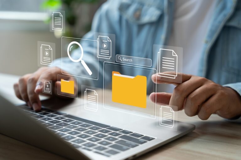 Person using a laptop with digital icons of documents, a search bar, and a folder overlayed, representing AI-powered automation for prior authorization and streamlined data processing.