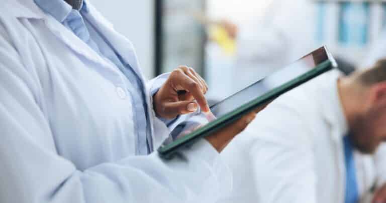 Healthcare professional using a tablet in a clinical setting, symbolizing data-driven management of targeted immunomodulator therapies.